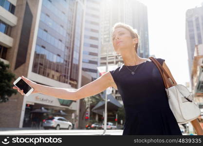 Businesswoman in a city street waving for taxi. I will be there in time for my meeting