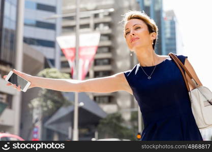 Businesswoman in a city street waving for taxi. I will be there in time for my meeting