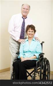 Businesswoman in a wheelchair and businessman standing beside her.