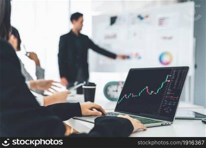 Businesswoman in analyze stock market data using laptop computer proficiently at the office while attending a group meeting with business team .. Stock Market Trading
