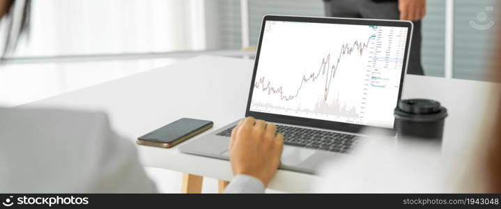 Businesswoman in analyze stock market data using laptop computer proficiently at the office while attending a group meeting with business team .. Businesswoman in analyze stock market data using laptop computer proficiently