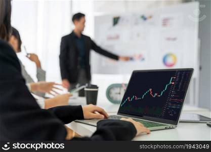 Businesswoman in analyze stock market data using laptop computer proficiently at the office while attending a group meeting with business team .. Stock Market Trading