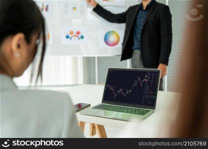 Businesswoman in analyze stock market data using laptop computer proficiently at the office while attending a group meeting with business team .. Businesswoman in analyze stock market data using laptop computer proficiently