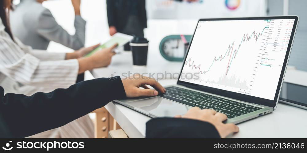 Businesswoman in analyze stock market data using laptop computer proficiently at the office while attending a group meeting with business team .. Businesswoman in analyze stock market data using laptop computer proficiently