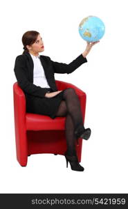 businesswoman in armchair holding globe