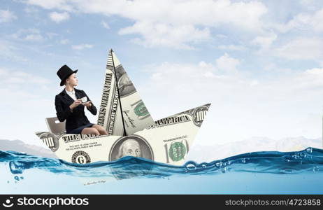 Businesswoman in boat made of dollar banknote. Successful businesswoman sailing on dollar boat in financial sea