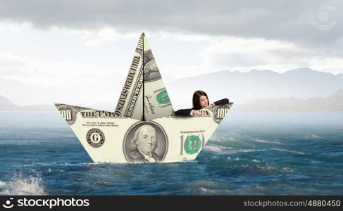 Businesswoman in boat made of dollar banknote. Successful businesswoman sailing on dollar boat in financial sea