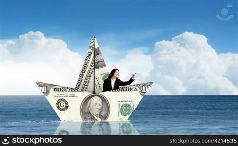 Businesswoman in boat made of dollar banknote. Successful businesswoman sailing on dollar boat in financial sea