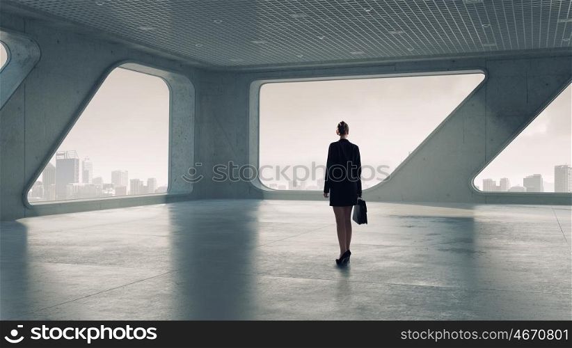 Businesswoman in building interior. Businesswoman in modern interior standing with back and looking in window