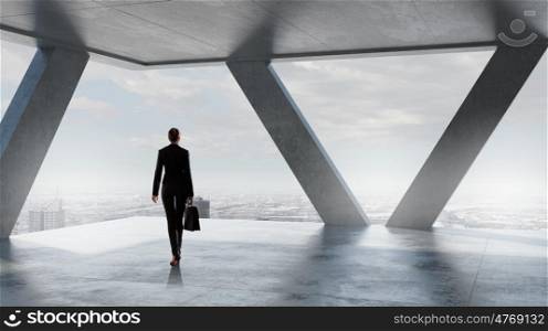 Businesswoman in building interior. Businesswoman standing with back and looking in office window