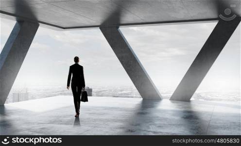 Businesswoman in building interior. Businesswoman standing with back and looking in office window