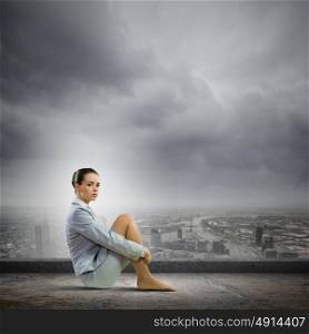 Businesswoman in despair. Image of young attractive businesswoman sitting alone atop of building