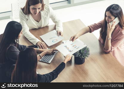 Businesswoman in group meeting discussion with other businesswomen colleagues in modern workplace office with laptop computer and documents on table. People corporate business working team concept.