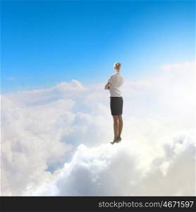 Businesswoman in heaven. Rear view of businesswoman standing on cloud high in sky