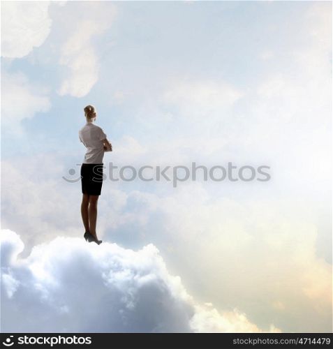 Businesswoman in heaven. Rear view of businesswoman standing on cloud high in sky