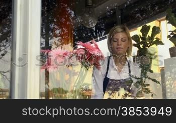 Businesswoman in her own flower shop, preparing bouquet and holding white roses. Dolly shot