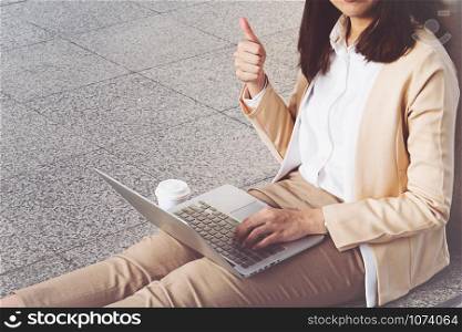 Businesswoman in high heels sitting on floor with computer in her lap
