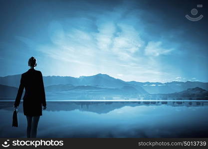 Businesswoman in isolation. Rear view of businesswoman looking at picturesque nature landscape