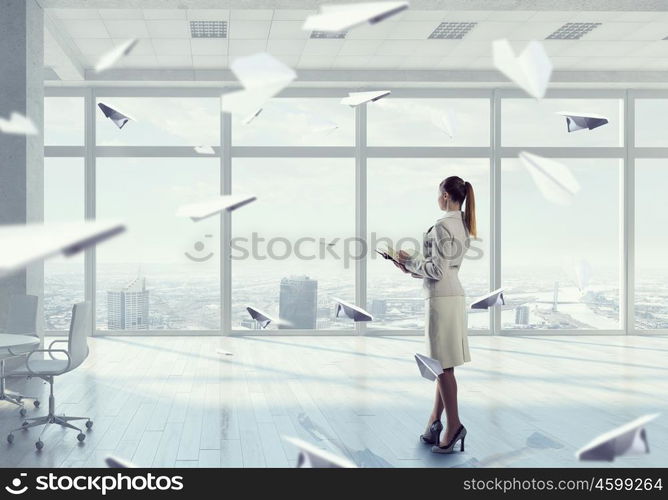 Businesswoman in modern office interior mixed media. Young successful businesswoman thinking about future of her company