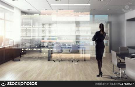 Businesswoman in modern office interior mixed media. Young successful businesswoman thinking about future of her company
