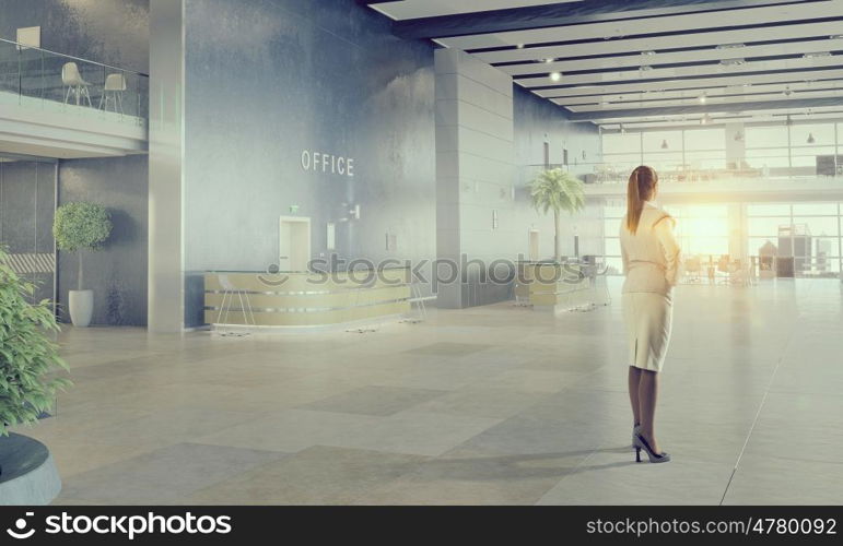 Businesswoman in modern office interior mixed media. Young successful businesswoman thinking about future of her company