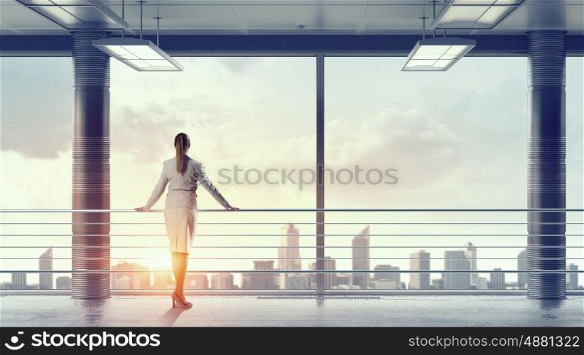 Businesswoman in modern office interior mixed media. Young successful businesswoman thinking about future of her company