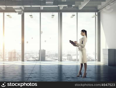 Businesswoman in modern office interior mixed media. Young successful businesswoman thinking about future of her company