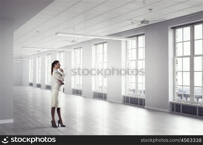 Businesswoman in modern office mixed media. Young elegant businesswoman in office interior thinking something over