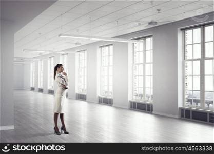 Businesswoman in modern office mixed media. Young elegant businesswoman in office interior thinking something over