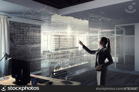 Businesswoman in modern office mixed media. Young elegant businesswoman in office working with virtual panel