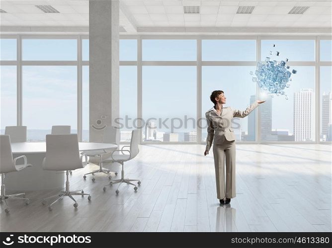 Businesswoman in office mixed media. Young successful businesswoman in white office interior and 3d cube figure in hand