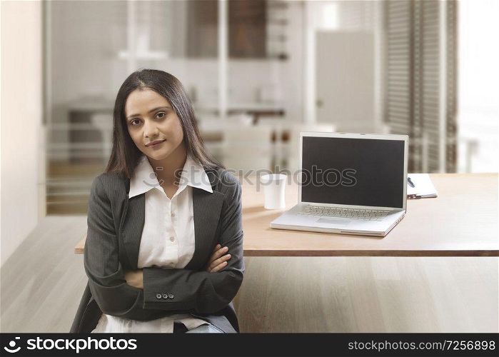 Businesswoman in office with arms crossed looking at camera