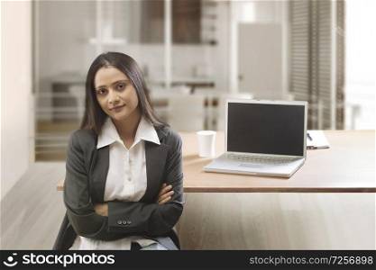 Businesswoman in office with arms crossed looking at camera