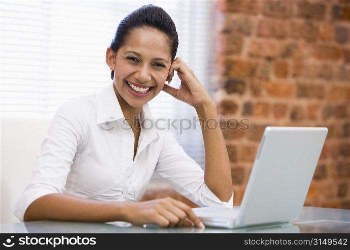 Businesswoman in office with laptop laughing