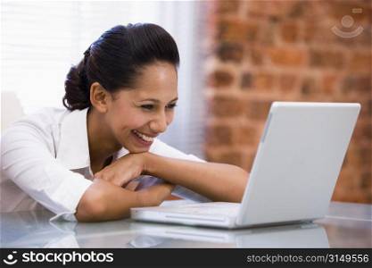 Businesswoman in office with laptop laughing
