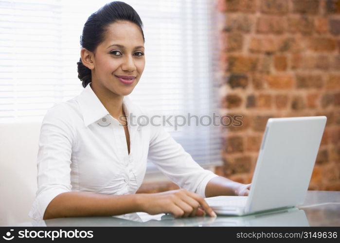 Businesswoman in office with laptop smiling