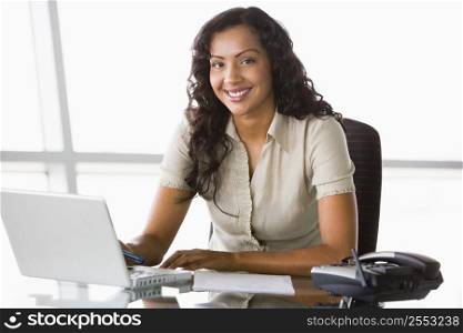 Businesswoman in office with laptop smiling (high key/selective focus)