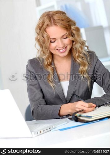 Businesswoman in office writing on agenda