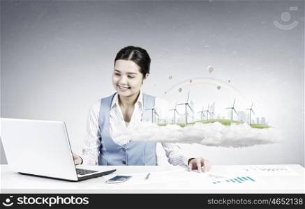Businesswoman in process of work. Young attractive businesswoman working at her desk with laptop and ecology project