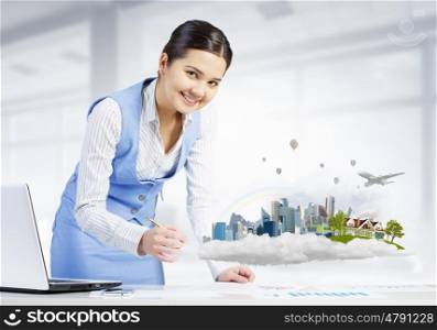 Businesswoman in process of work. Young attractive businesswoman working at her desk with laptop and construction project