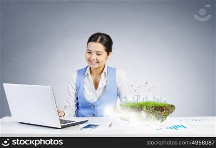 Businesswoman in process of work. Young attractive businesswoman working at her desk with laptop and ecology project