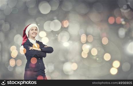 Businesswoman in Santa hat. Woman in suit and Santa hat with arms crossed on chest