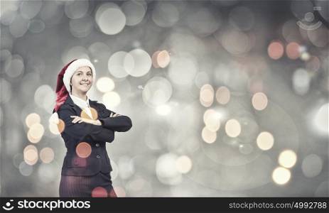 Businesswoman in Santa hat. Woman in suit and Santa hat with arms crossed on chest