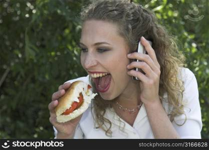 Businesswoman in the park about to take a big bite out of her white healthy bun