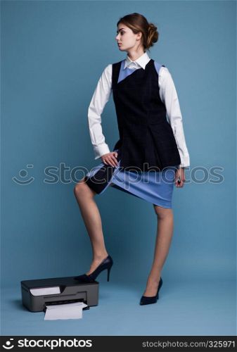 Businesswoman in working suit standing with her feet on printer in studio with blue background