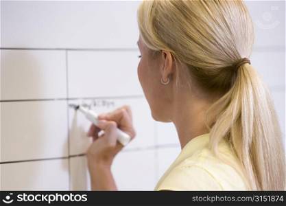 Businesswoman indoors writing on erasable board