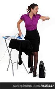 Businesswoman ironing and looking at the time
