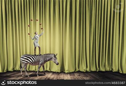 Businesswoman juggling with balls. Young businesswoman standing on zebra and juggling with balls