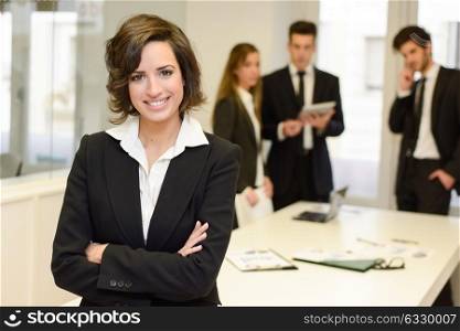 Businesswoman leader looking at camera in working environment. Young woman wearing black blazer jacket