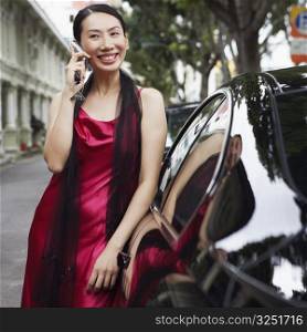 Businesswoman leaning against a car and talking on a mobile phone